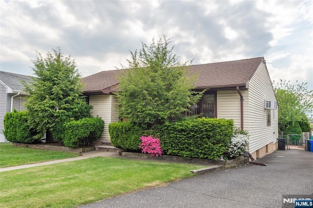 obstructed view of property featuring a shingled roof and a front yard