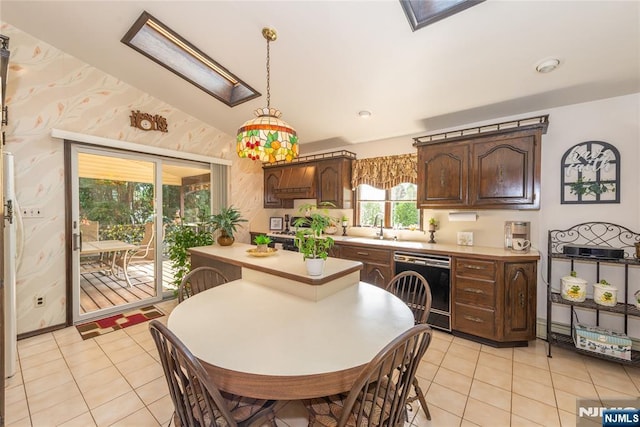 dining room featuring a skylight, light tile patterned flooring, vaulted ceiling, and wallpapered walls