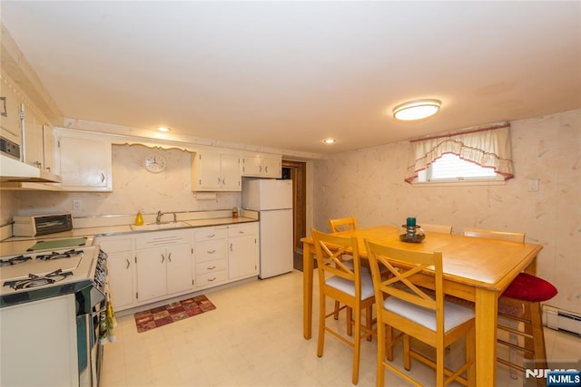 kitchen featuring freestanding refrigerator, gas range oven, a sink, light floors, and white cabinets