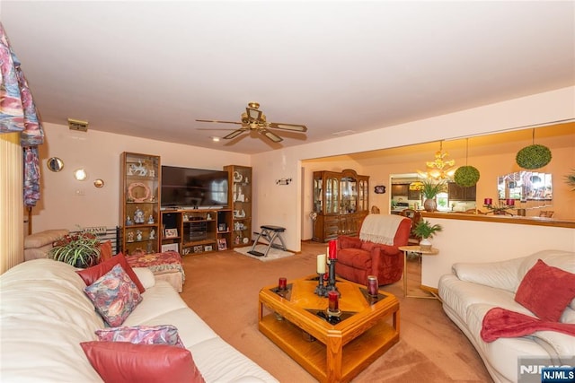carpeted living room with ceiling fan and a chandelier
