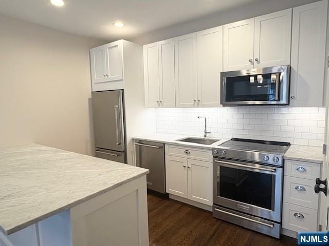 kitchen featuring appliances with stainless steel finishes, a sink, recessed lighting, dark wood-style floors, and white cabinets