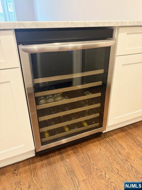 kitchen view of white cabinetry, wine cooler, dark wood finished floors, and light countertops