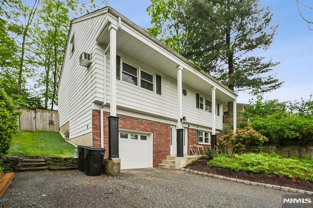 11 Beech Ct, Ringwood, NJ 07456 - view of front of home featuring brick siding, a garage, fence, a wall unit AC, and asphalt driveway