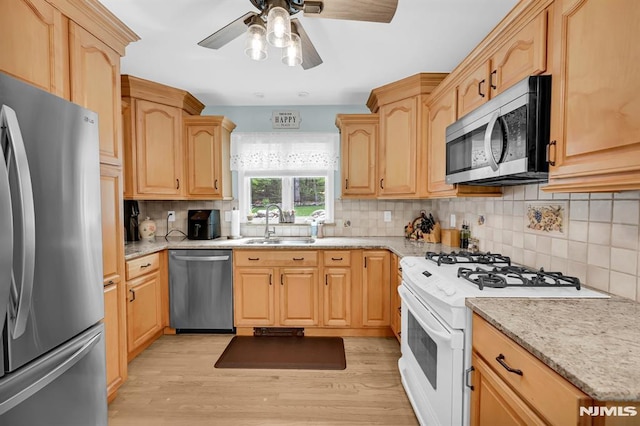 kitchen with stainless steel appliances, a sink, light wood-style flooring, a ceiling fan, and light brown cabinets