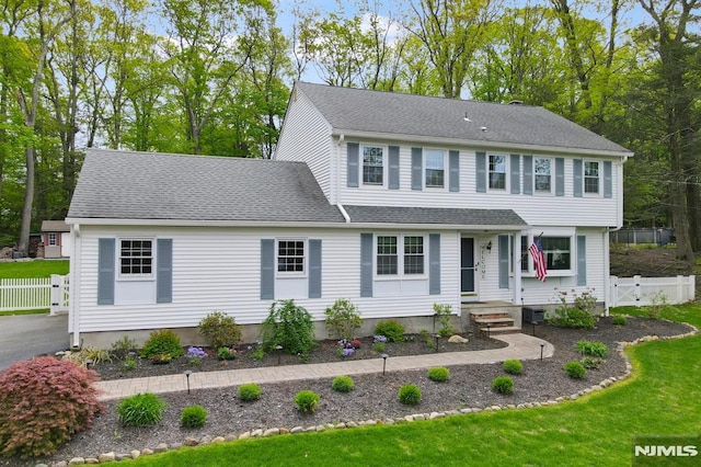 colonial house featuring roof with shingles