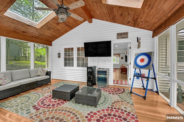 living room with a skylight, wooden ceiling, wood finished floors, a ceiling fan, and vaulted ceiling