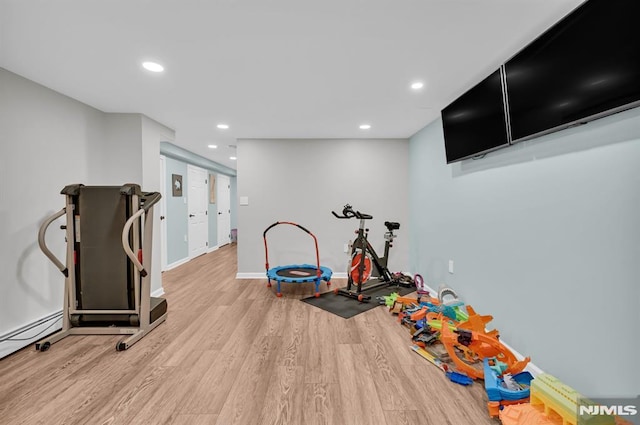 workout room featuring wood finished floors, recessed lighting, baseboards, and baseboard heating