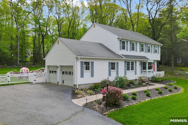 colonial inspired home featuring a gate, a shingled roof, driveway, and view of scattered trees
