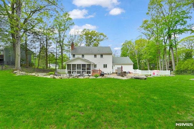 back of house featuring a sunroom, a chimney, and a patio