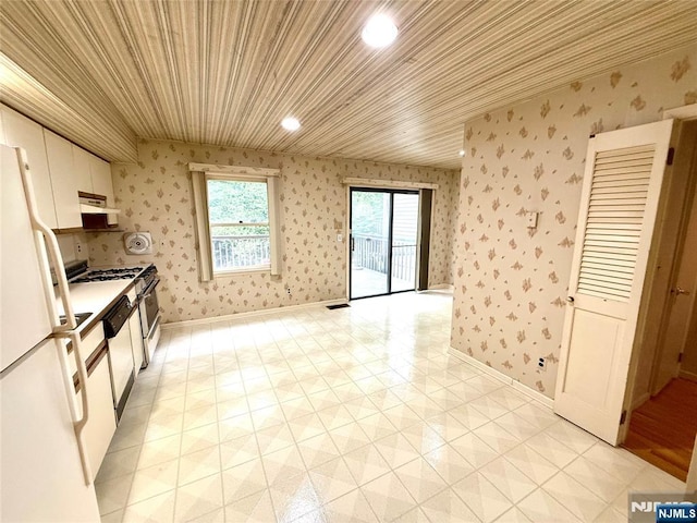 kitchen featuring white appliances, wallpapered walls, wood ceiling, under cabinet range hood, and white cabinetry