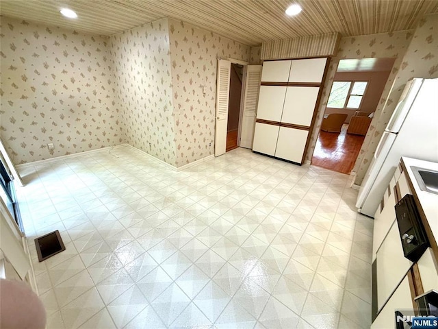 spare room featuring wallpapered walls, wooden ceiling, recessed lighting, baseboards, and a sink
