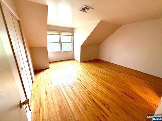 additional living space with hardwood / wood-style flooring and vaulted ceiling