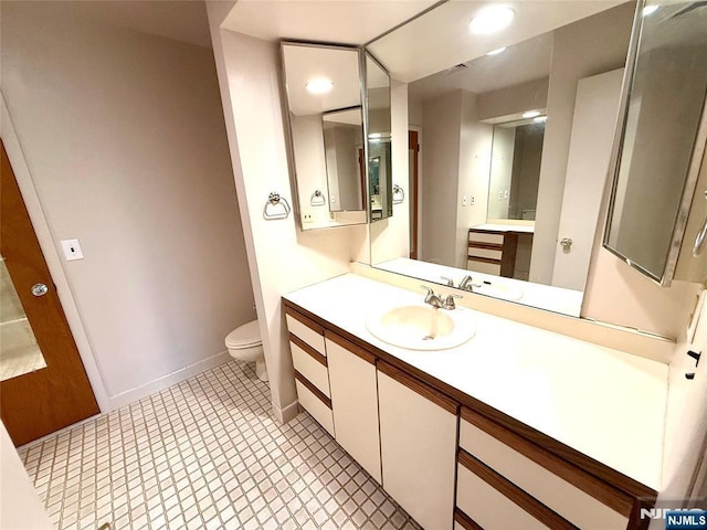 bathroom with toilet, vanity, and baseboards