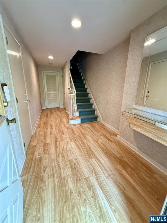 hallway featuring light wood-style floors, stairs, baseboards, and recessed lighting