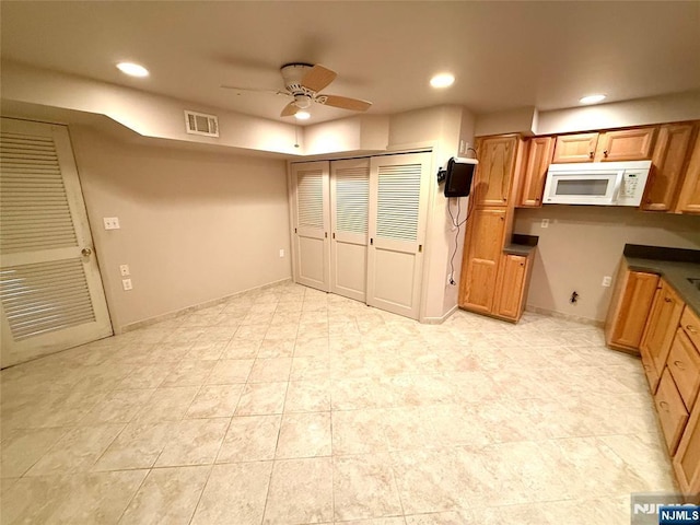 kitchen featuring white microwave, ceiling fan, brown cabinetry, recessed lighting, and dark countertops