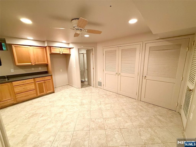kitchen with dark countertops, recessed lighting, ceiling fan, light tile patterned floors, and brown cabinetry
