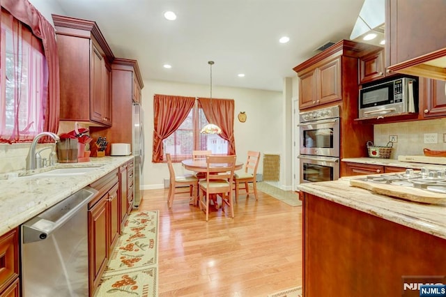 kitchen featuring appliances with stainless steel finishes, a sink, decorative backsplash, light stone counters, and recessed lighting