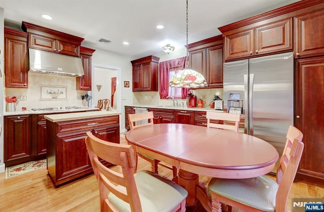 kitchen with under cabinet range hood, light wood-type flooring, appliances with stainless steel finishes, recessed lighting, and light countertops