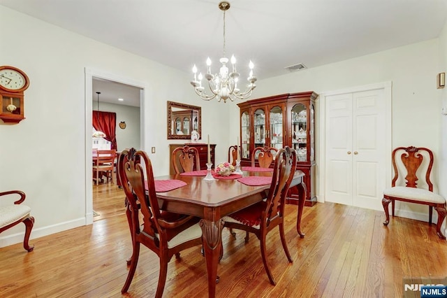 dining room with light wood-type flooring, a chandelier, and baseboards