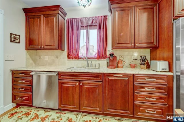 kitchen with stainless steel appliances, a sink, decorative backsplash, and light stone countertops
