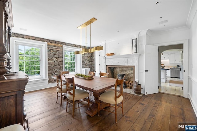 868 Goffle Rd, Hawthorne, NJ 07506 - dining space featuring dark wood-style flooring, a fireplace, radiator, arched walkways, and ornamental molding