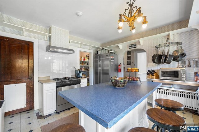 868 Goffle Rd, Hawthorne, NJ 07506 - kitchen with appliances with stainless steel finishes, radiator heating unit, light tile patterned flooring, a chandelier, and arched walkways