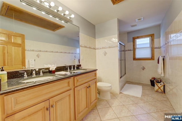 543 Page Ave, Lyndhurst, NJ 07071 - full bathroom featuring tile patterned floors, double vanity, toilet, tile walls, and washtub / shower combination