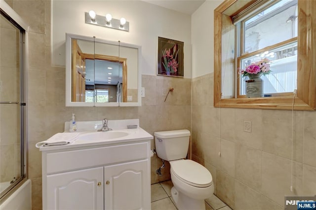 543 Page Ave, Lyndhurst, NJ 07071 - bathroom featuring tile walls, toilet, tile patterned floors, vanity, and shower / bath combination with glass door