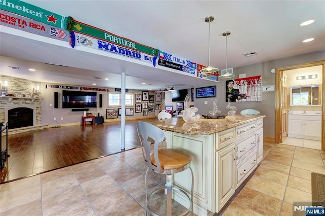 543 Page Ave, Lyndhurst, NJ 07071 - kitchen with open floor plan, a breakfast bar, light stone counters, a fireplace, and light tile patterned floors