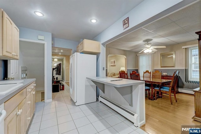 kitchen featuring freestanding refrigerator, baseboard heating, a ceiling fan, and light countertops
