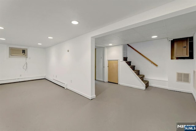 finished basement with an AC wall unit, recessed lighting, baseboards, stairway, and electric panel