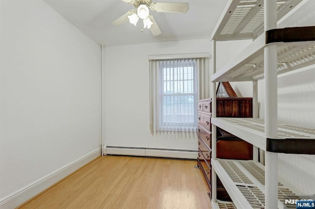 unfurnished bedroom featuring baseboard heating, wood finished floors, and baseboards