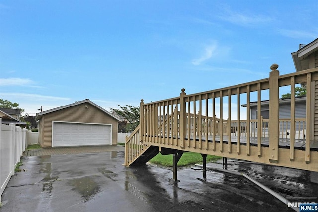 wooden deck with an outdoor structure, a detached garage, and fence