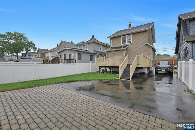 rear view of property with a residential view, fence, a deck, stairs, and a chimney