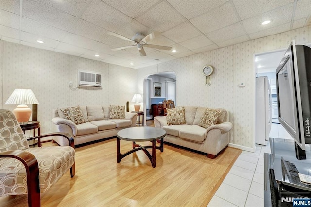 living room with arched walkways, ceiling fan, wallpapered walls, light tile patterned floors, and a wall unit AC