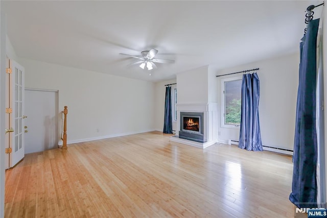 38 Pitcairn Ave, Ho-Ho-Kus, NJ 07423 - unfurnished living room featuring a baseboard heating unit, light wood finished floors, ceiling fan, and a lit fireplace