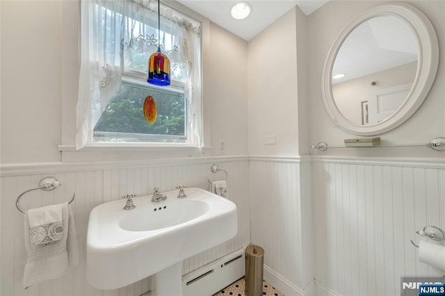 bathroom featuring a baseboard heating unit, a wainscoted wall, and healthy amount of natural light