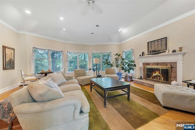 living room with plenty of natural light, recessed lighting, a brick fireplace, wood finished floors, and ornamental molding