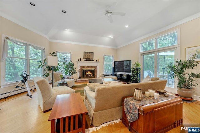 living area with plenty of natural light, ceiling fan, light wood finished floors, a brick fireplace, and crown molding