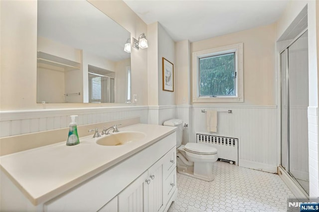 full bath featuring radiator, wainscoting, a stall shower, vanity, and toilet