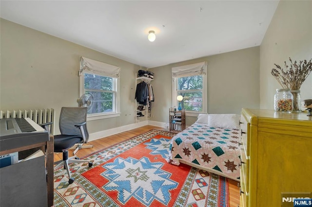 bedroom with wood finished floors, baseboards, and radiator heating unit