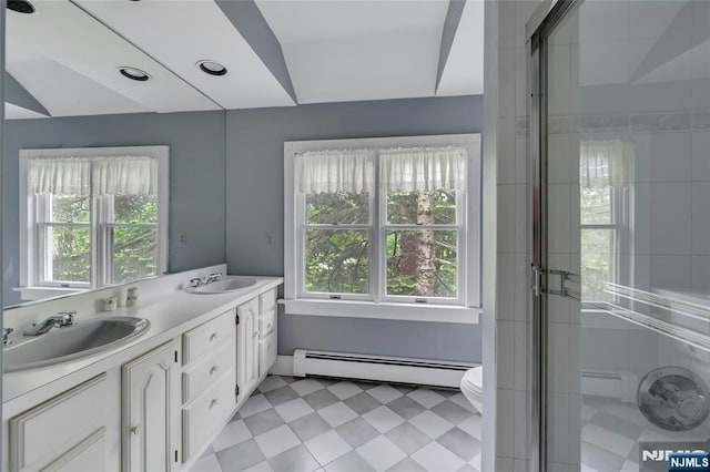 bathroom featuring baseboard heating, plenty of natural light, double vanity, and toilet