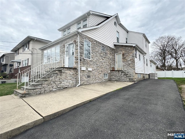 717 1st St, Lyndhurst, NJ 07071 - view of property exterior featuring stone siding, fence, and cooling unit