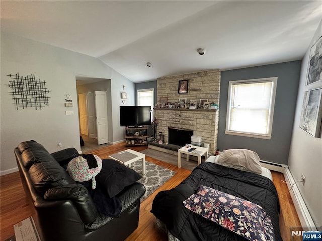 717 1st St, Lyndhurst, NJ 07071 - living room featuring baseboard heating, vaulted ceiling, wood finished floors, a stone fireplace, and baseboards