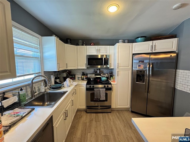 717 1st St, Lyndhurst, NJ 07071 - kitchen featuring appliances with stainless steel finishes, a sink, light wood-style flooring, light countertops, and white cabinetry