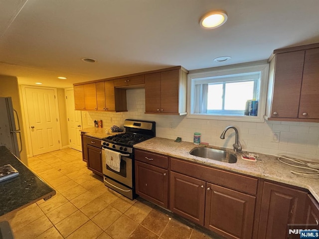 717 1st St, Lyndhurst, NJ 07071 - kitchen featuring stainless steel gas range oven, a sink, freestanding refrigerator, decorative backsplash, and light tile patterned flooring