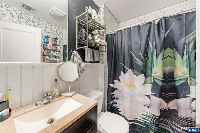 bathroom with wallpapered walls, toilet, vanity, and curtained shower