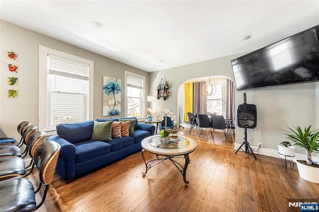 living room featuring arched walkways, wood finished floors, and baseboards