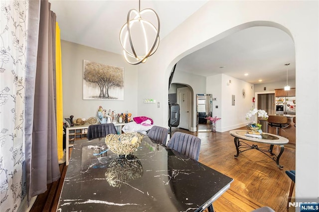 dining room featuring arched walkways, wood finished floors, recessed lighting, and baseboards
