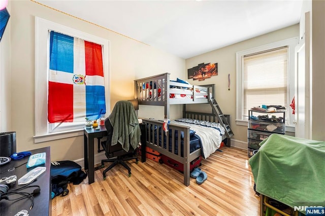 bedroom with multiple windows, wood finished floors, and baseboards